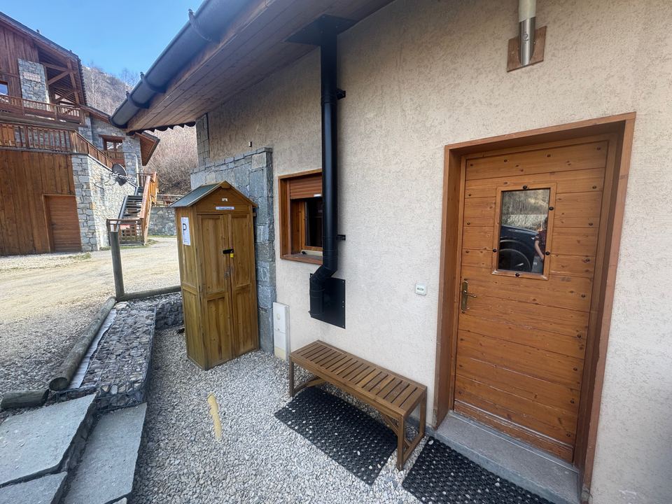 The front door, with the chalet's own ski cupboard and the bench to pull your boots on. The parking space is a few steps to the left.