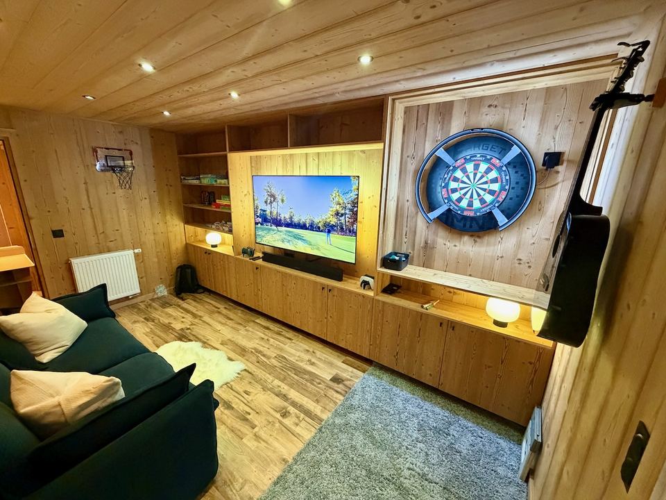 The games room, which doubles as Bedroom 3 — soft-tip darts, mini basketball and a 65" screen.