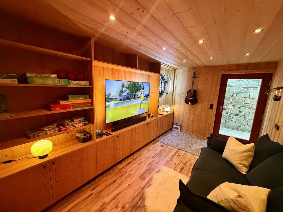 A cupboard of board games, the guitar, and the PS5 on the second screen.